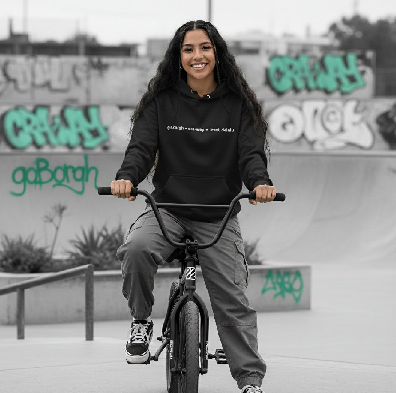 Woman riding a bike wearing a black cra-way math delulu oversized hoodie in an urban setting