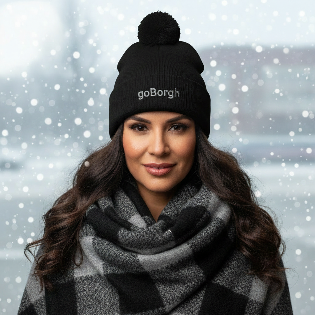 Woman wearing a black goBorgh knit beanie with pom in a snowy winter setting