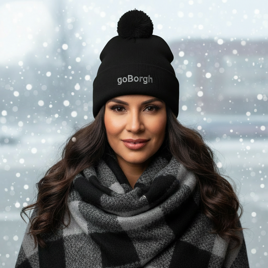 Woman wearing a black goBorgh knit beanie with pom in a snowy winter setting