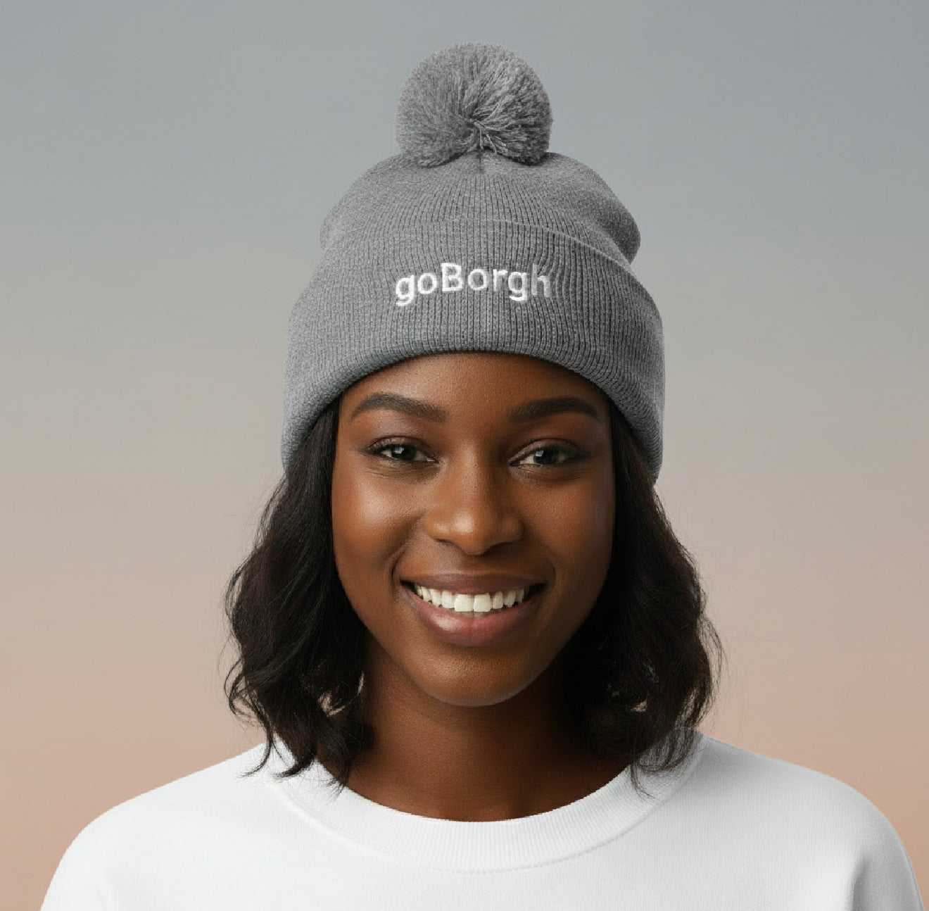 Close-up portrait of a woman wearing a gray goBorgh knit beanie with pom