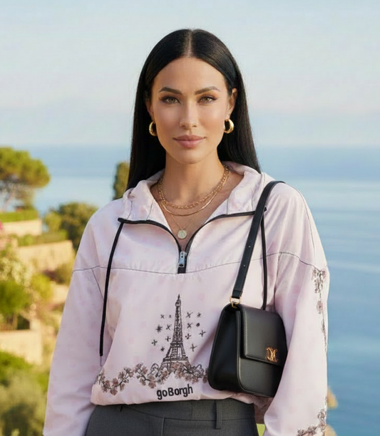 Model wearing pale pink goBorgh Paris in Bloom Eiffel Tower cherry blossom half zip windbreaker with cropped fit and lightweight design, styled outdoors by the coast