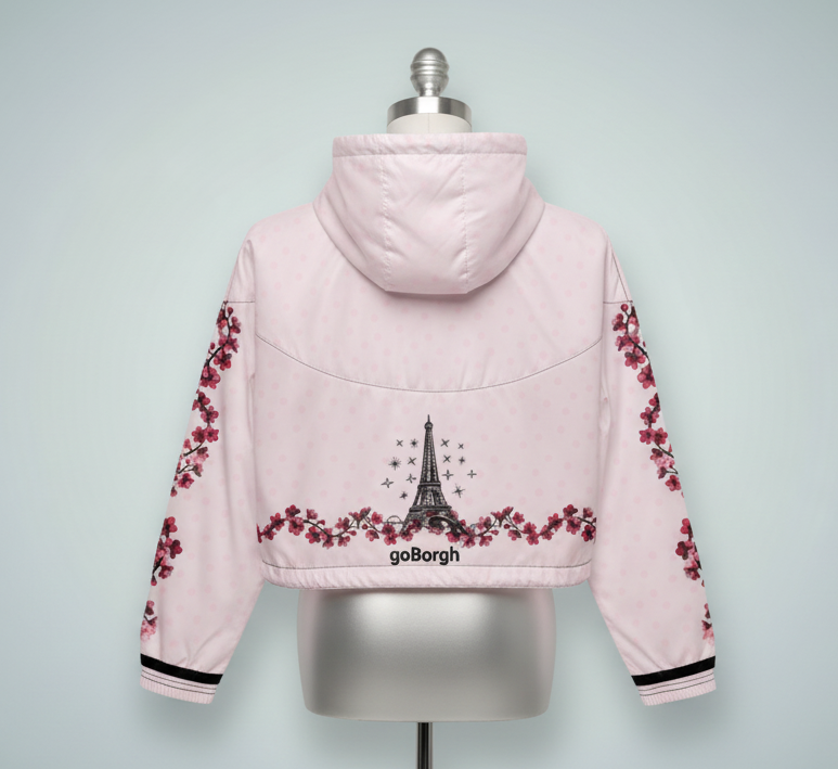 Studio back view of pale pink goBorgh brand Paris in Bloom Eiffel Tower cherry blossom half zip windbreaker highlighting hood, cherry blossom detailing, and cropped silhouette